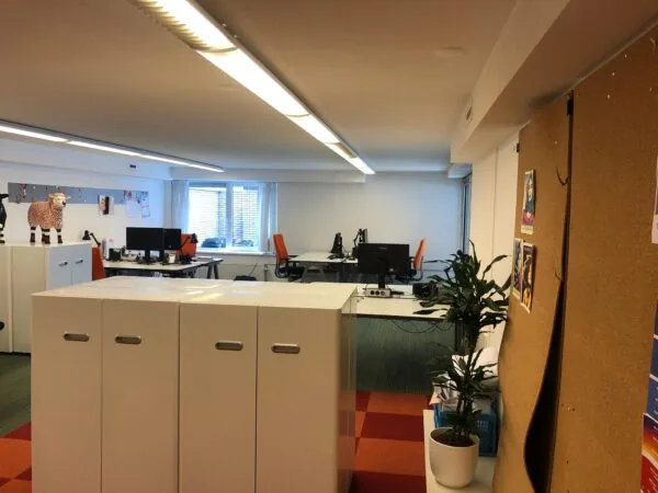 Modern kantoorinterieur aan de Prins Hendrikkade met bureaus, computers en een prikbord aan de muur.